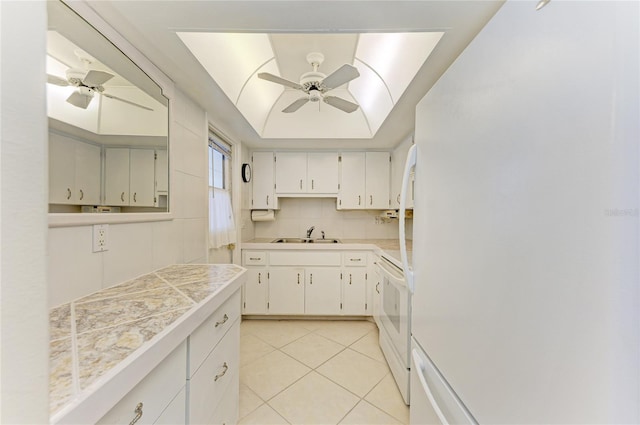 kitchen featuring white appliances, decorative backsplash, a raised ceiling, a ceiling fan, and light tile patterned flooring