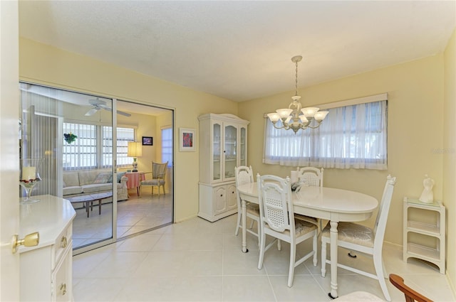 dining area with light tile patterned flooring, a textured ceiling, baseboards, and ceiling fan with notable chandelier