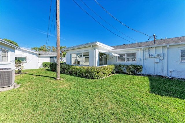 rear view of property featuring central AC and a lawn