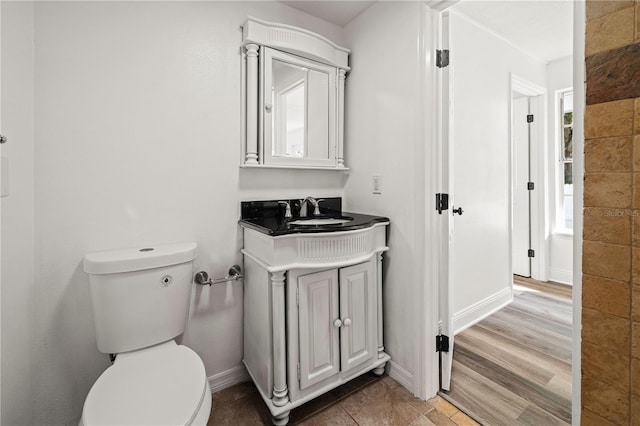 bathroom with toilet, baseboards, wood finished floors, and vanity