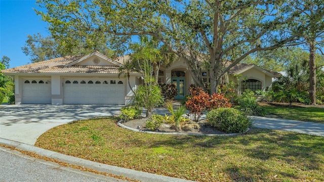 view of front of property featuring an attached garage, stucco siding, concrete driveway, french doors, and a tiled roof