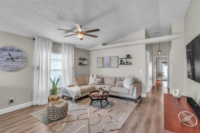 living room with lofted ceiling, ceiling fan, a textured ceiling, and wood finished floors