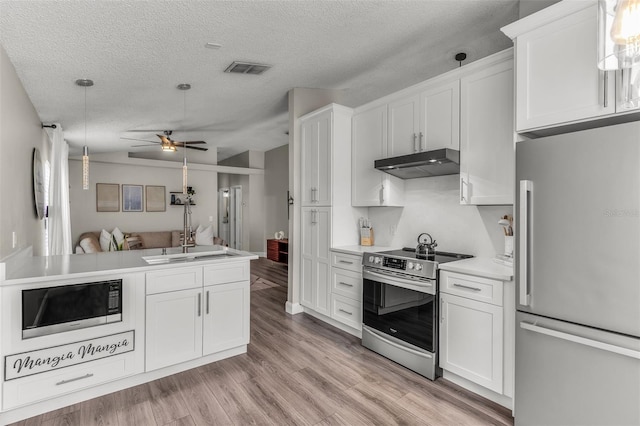 kitchen featuring appliances with stainless steel finishes, light wood-style floors, white cabinets, a sink, and under cabinet range hood