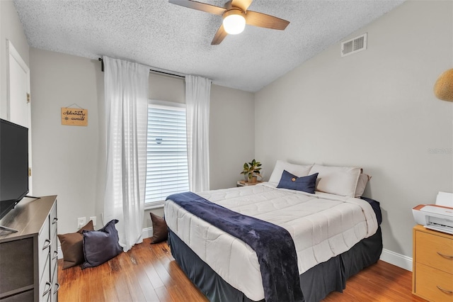 bedroom with visible vents, ceiling fan, a textured ceiling, and wood finished floors