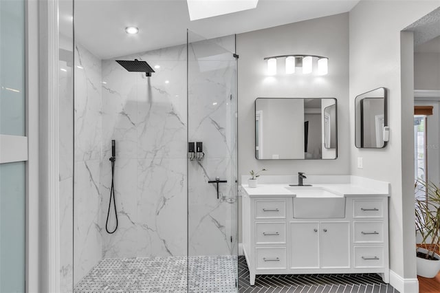 full bath featuring baseboards, vanity, and a marble finish shower