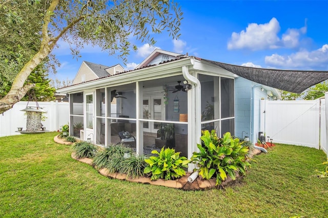 view of side of home with fence private yard, a sunroom, a ceiling fan, a lawn, and a gate