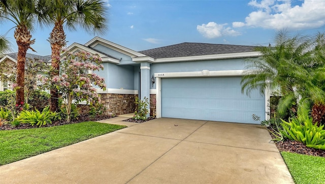 view of front of property with concrete driveway, roof with shingles, an attached garage, and stucco siding