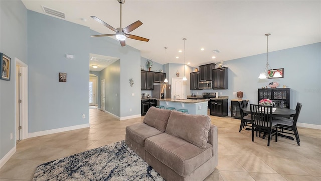 living area with a ceiling fan, visible vents, baseboards, and light tile patterned floors