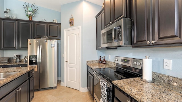 kitchen featuring light tile patterned floors, stainless steel appliances, baseboards, and light stone countertops