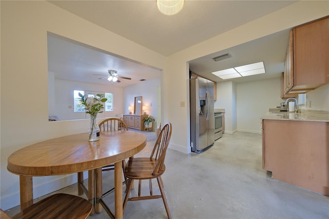 dining room with a skylight, visible vents, baseboards, a ceiling fan, and concrete flooring