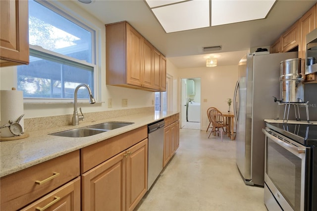 kitchen featuring a sink, visible vents, appliances with stainless steel finishes, light stone countertops, and washer / clothes dryer