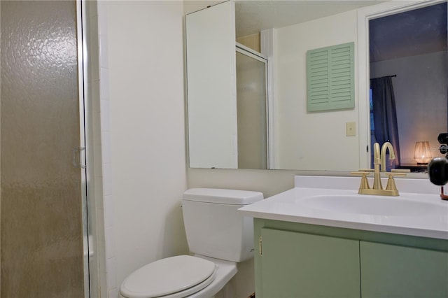 bathroom featuring toilet, a shower stall, and vanity