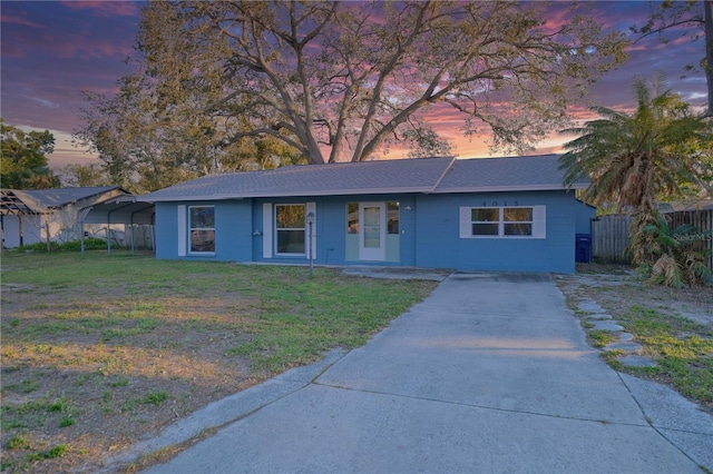 single story home with driveway, a lawn, and fence