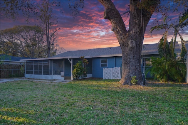 view of front of home with a lawn, fence, and a sunroom