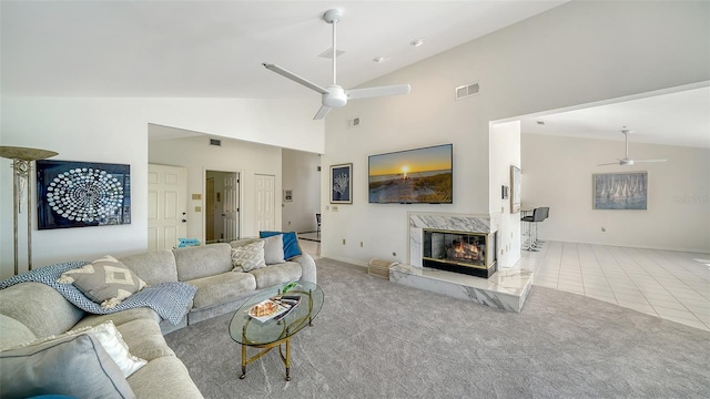 living area with visible vents, a premium fireplace, carpet flooring, and a ceiling fan