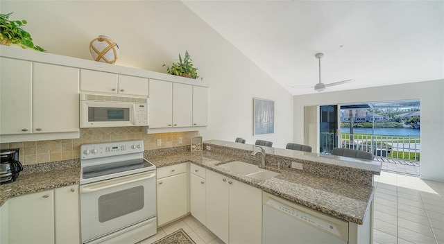 kitchen featuring backsplash, light tile patterned flooring, a sink, white appliances, and a peninsula