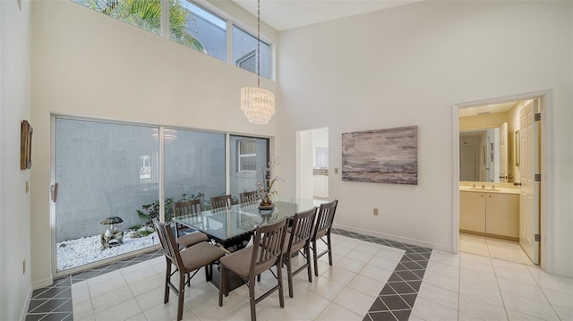 dining area featuring a chandelier, light tile patterned floors, a towering ceiling, and baseboards