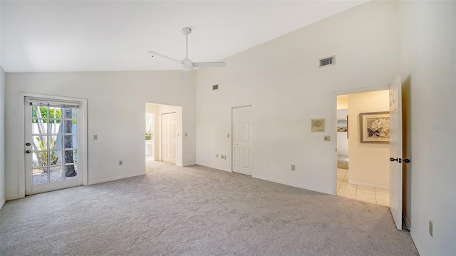 interior space with light carpet, high vaulted ceiling, visible vents, and baseboards