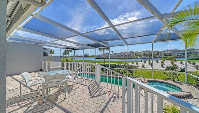 view of patio featuring outdoor dining area, glass enclosure, a water view, and an in ground hot tub