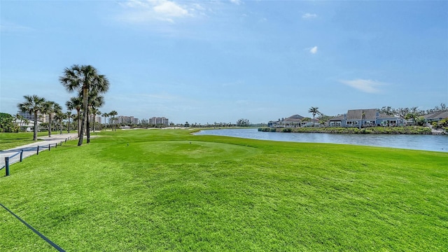 surrounding community with a water view and a lawn