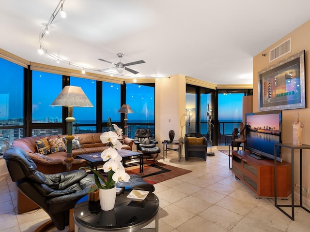 living area with expansive windows, visible vents, and a ceiling fan