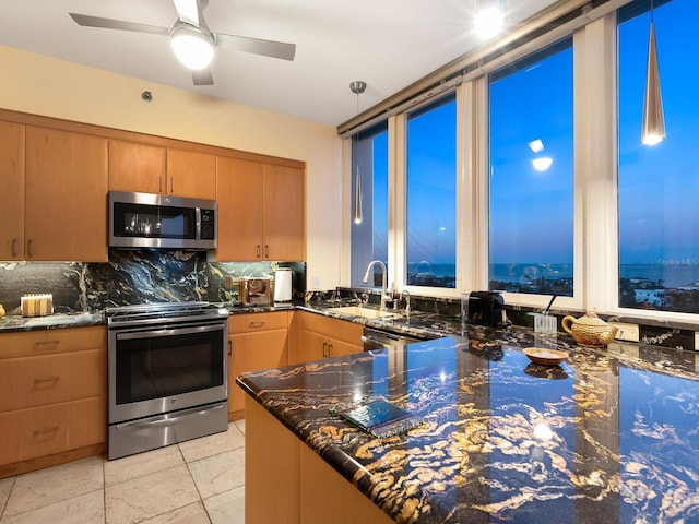 kitchen with light tile patterned floors, appliances with stainless steel finishes, backsplash, dark stone countertops, and a sink