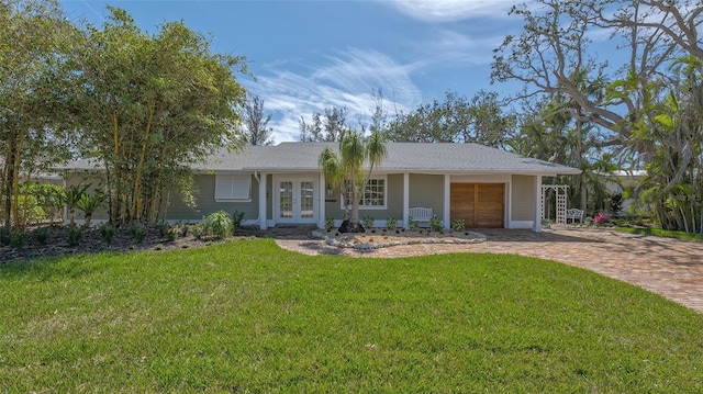 ranch-style home featuring french doors, decorative driveway, and a front yard