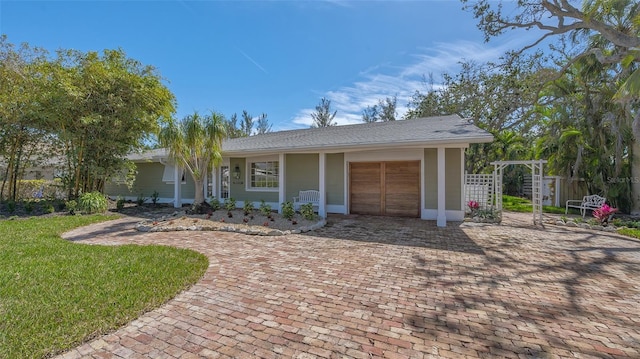 single story home featuring decorative driveway, a front lawn, an attached garage, and fence