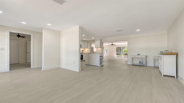 unfurnished living room featuring light wood-type flooring, baseboards, and a ceiling fan