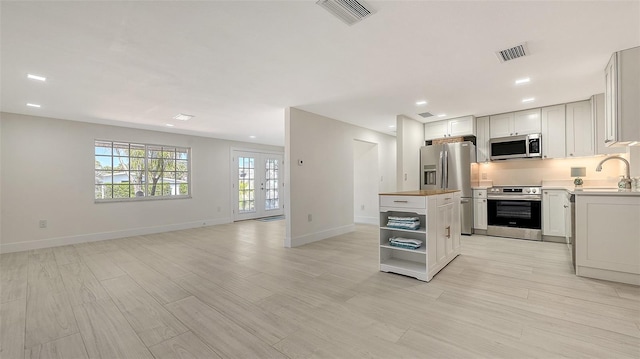 kitchen with appliances with stainless steel finishes, visible vents, light wood finished floors, and open shelves