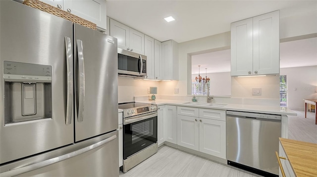 kitchen featuring stainless steel appliances, white cabinetry, and a sink