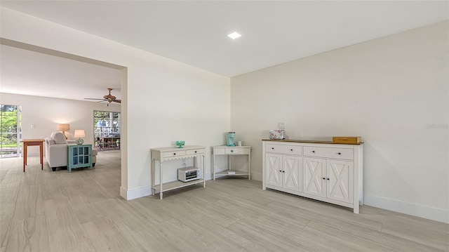 bar featuring a ceiling fan, light wood-style flooring, and baseboards