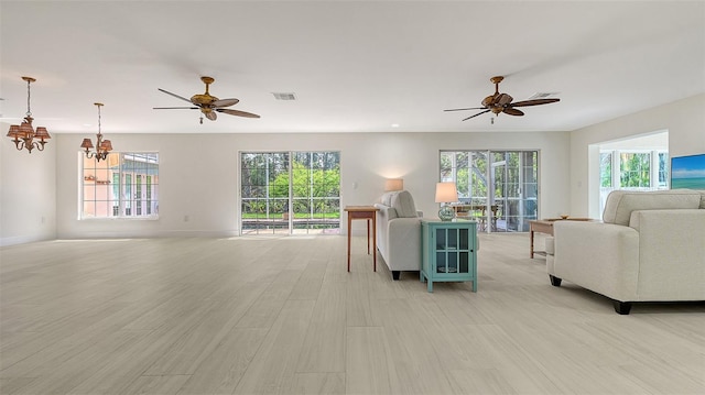 living area featuring a wealth of natural light, light wood-type flooring, and visible vents