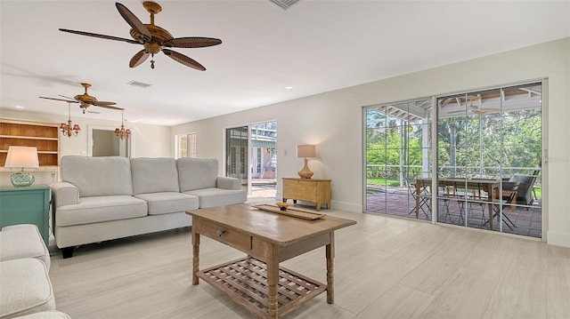 living room with recessed lighting, ceiling fan with notable chandelier, visible vents, baseboards, and light wood-style floors