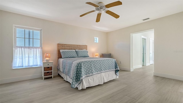 bedroom featuring a ceiling fan, visible vents, baseboards, and wood finished floors