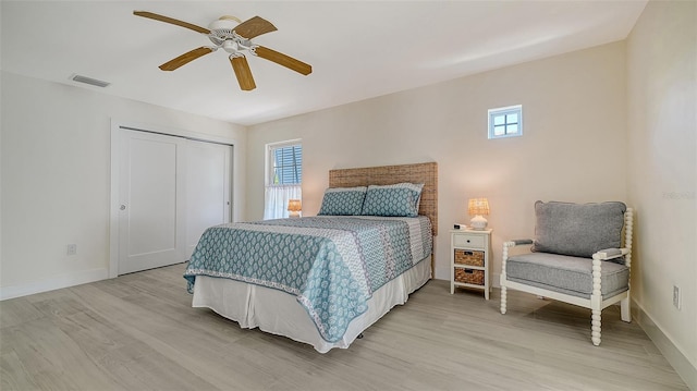 bedroom featuring a ceiling fan, baseboards, visible vents, light wood-style floors, and a closet