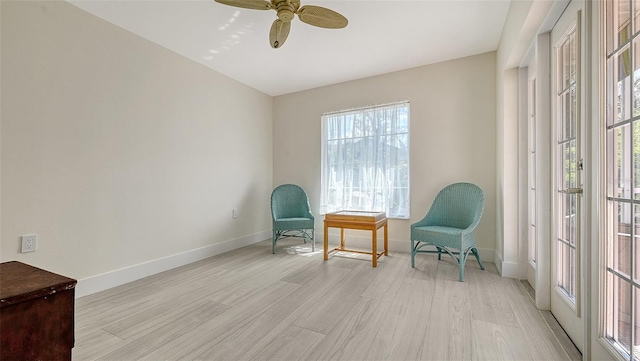 sitting room featuring light wood-style flooring, baseboards, and ceiling fan