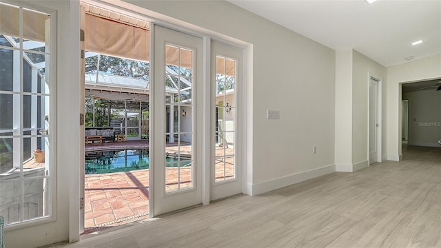 doorway featuring light wood-style flooring and baseboards