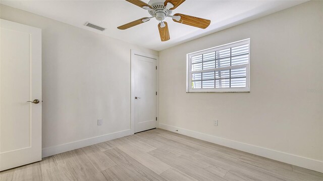 empty room featuring light wood finished floors, a ceiling fan, visible vents, and baseboards