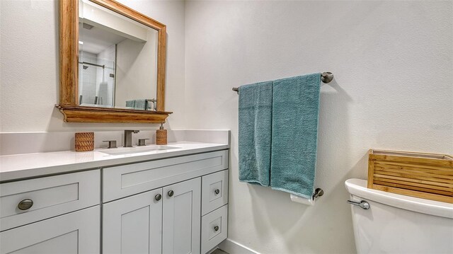 bathroom with toilet, a shower, and vanity