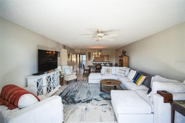 living room with ceiling fan with notable chandelier and a textured ceiling