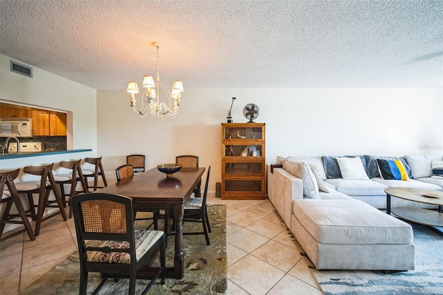 dining room with visible vents, a textured ceiling, an inviting chandelier, and light tile patterned floors