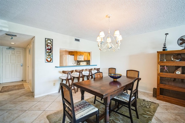 dining space featuring a textured ceiling, light tile patterned flooring, visible vents, and an inviting chandelier