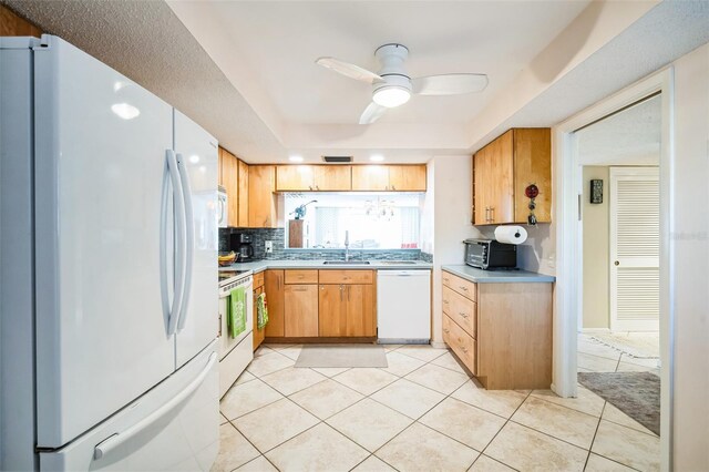 kitchen with light tile patterned floors, white appliances, a sink, light countertops, and backsplash