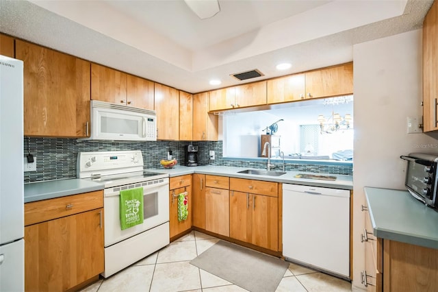 kitchen with white appliances, a sink, visible vents, and decorative backsplash