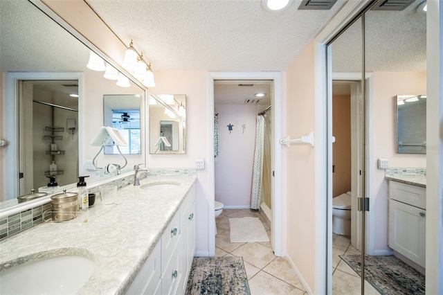 bathroom featuring a sink, a textured ceiling, toilet, and tile patterned floors