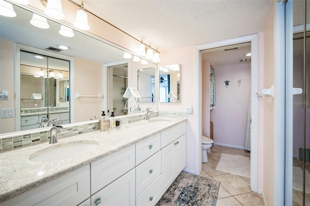 bathroom featuring a textured ceiling, tile patterned flooring, a sink, and toilet