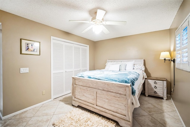 bedroom featuring a closet, ceiling fan, a textured ceiling, and light tile patterned floors