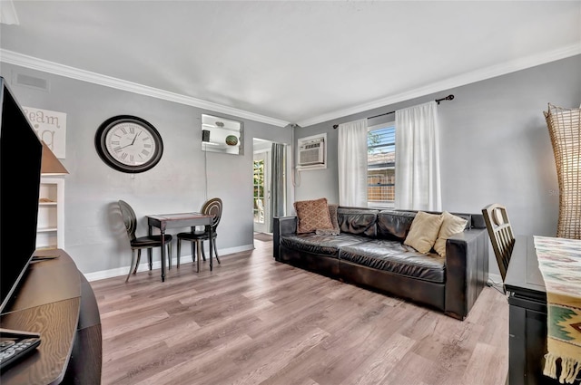 living room with an AC wall unit, ornamental molding, wood finished floors, and baseboards