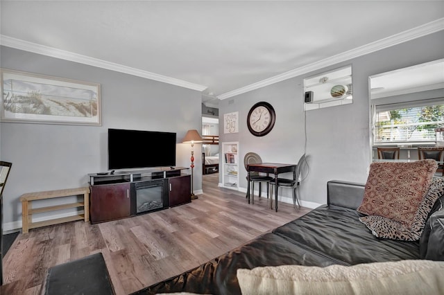 living area with baseboards, wood finished floors, and crown molding